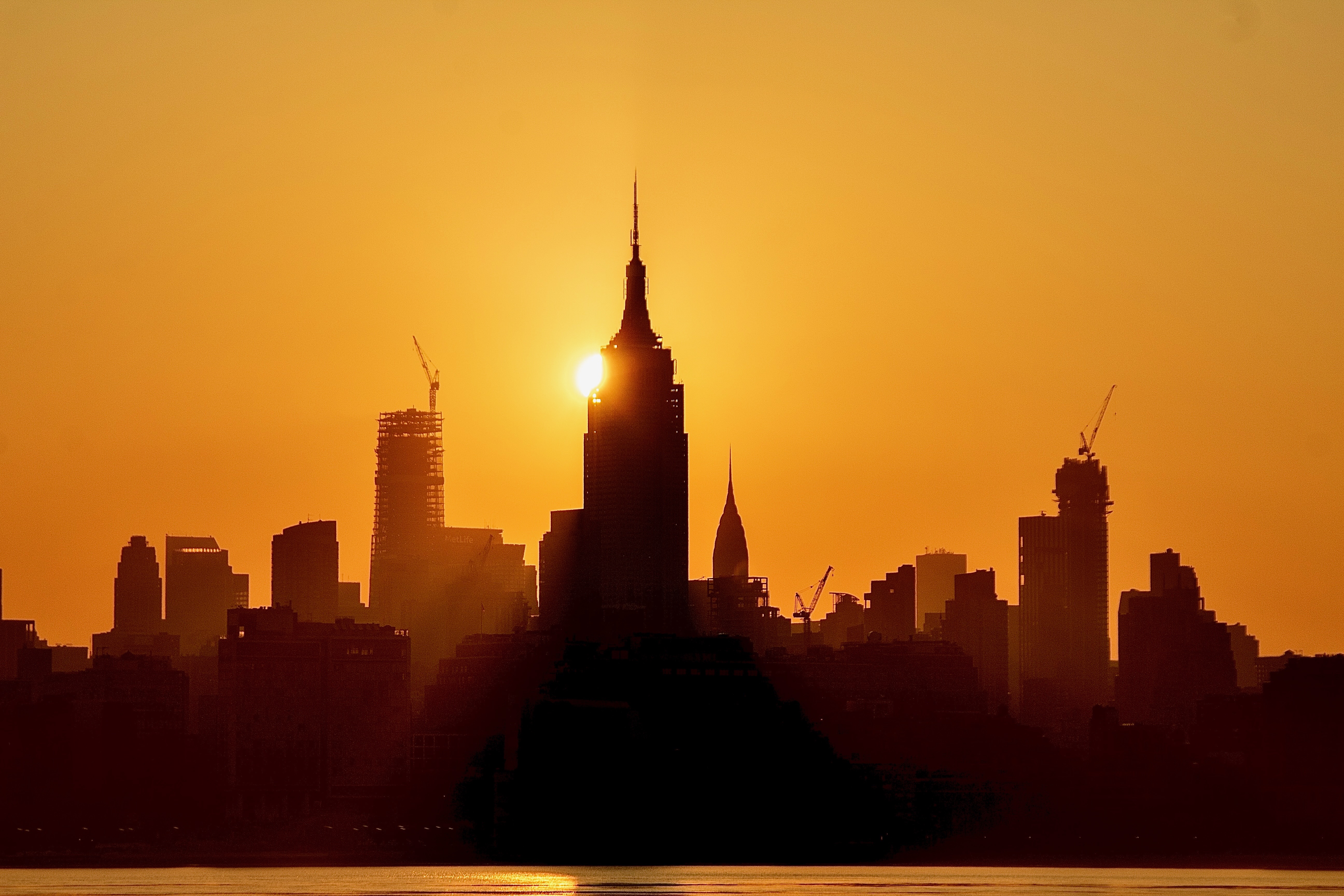 Manhattan skyline silhouetted against a molten orange sunset